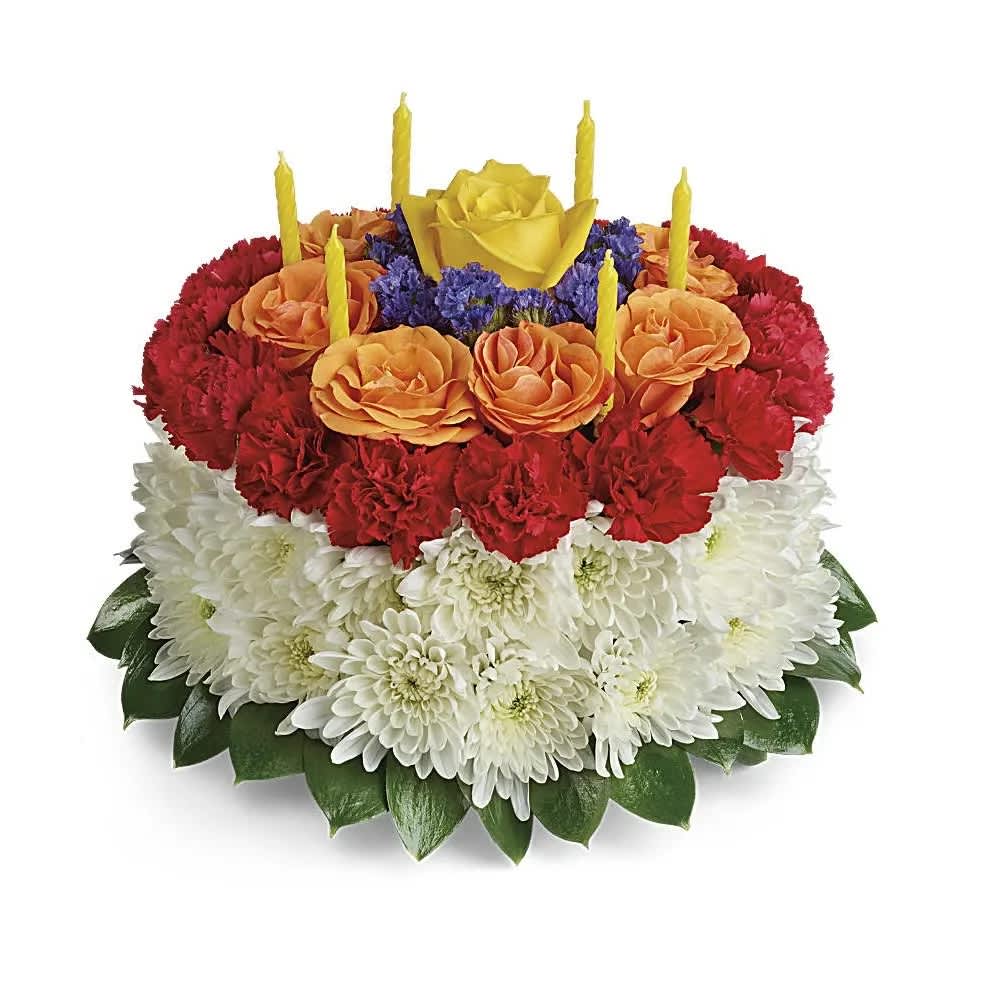 Your Wish Is Granted Birthday Cake Bouquet - Sweet as a birthday cake, this creative, colorful bouquet of roses and mums, topped with birthday candles, is sure to delight them on their special day! This cute cake arrangement is made up of yellow roses, orange and red spray roses, white cushion spray chrysanthemums, blue sinuata statice, and israeli ruscus. Delivered on a designer tray. Orientation: All-Around