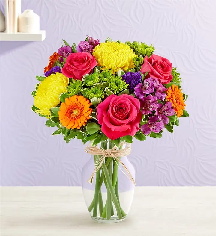 Colorful bouquet of roses, chrysanthemums, and gerbera daisies in a glass vase