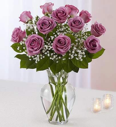 Lavender roses arranged in a clear glass vase with baby's breath