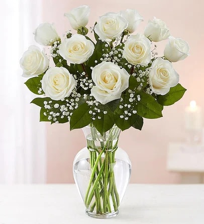 White roses arranged in a clear glass vase with baby's breath