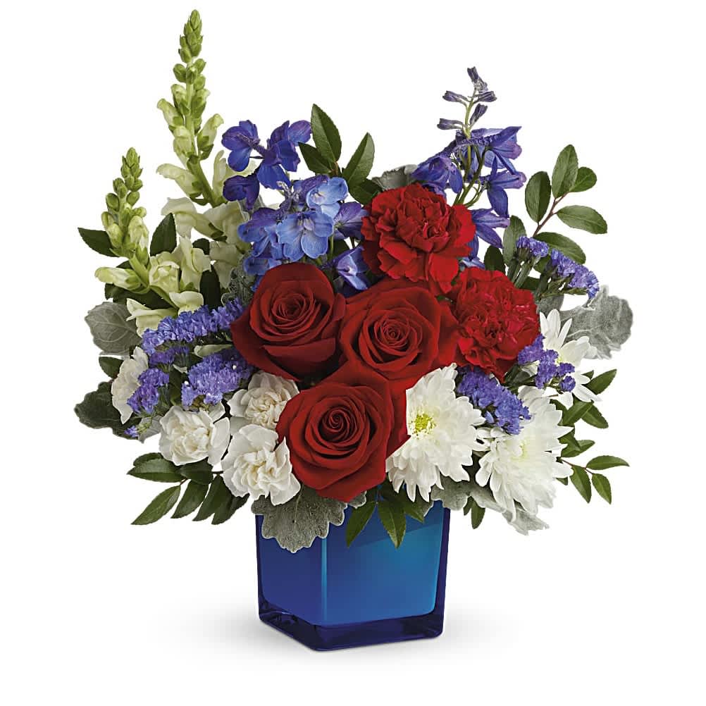 Red roses, white daisies, and purple flowers in a blue square vase