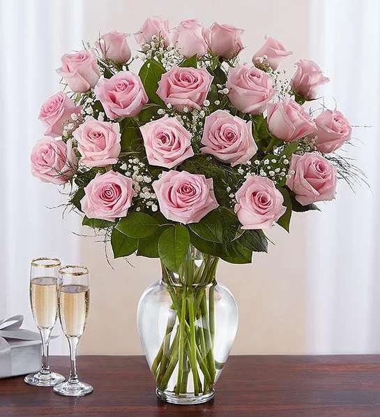 Pink roses arranged in a clear glass vase with baby's breath