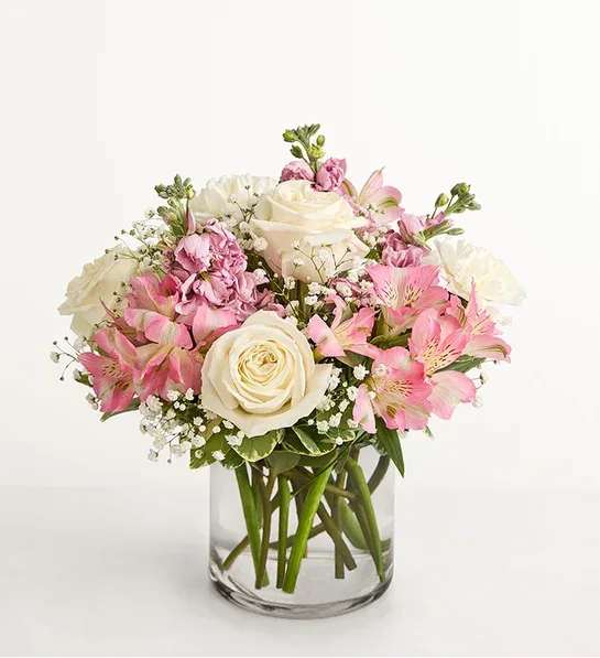 Pink and white bouquet of roses and lilies in a clear glass vase