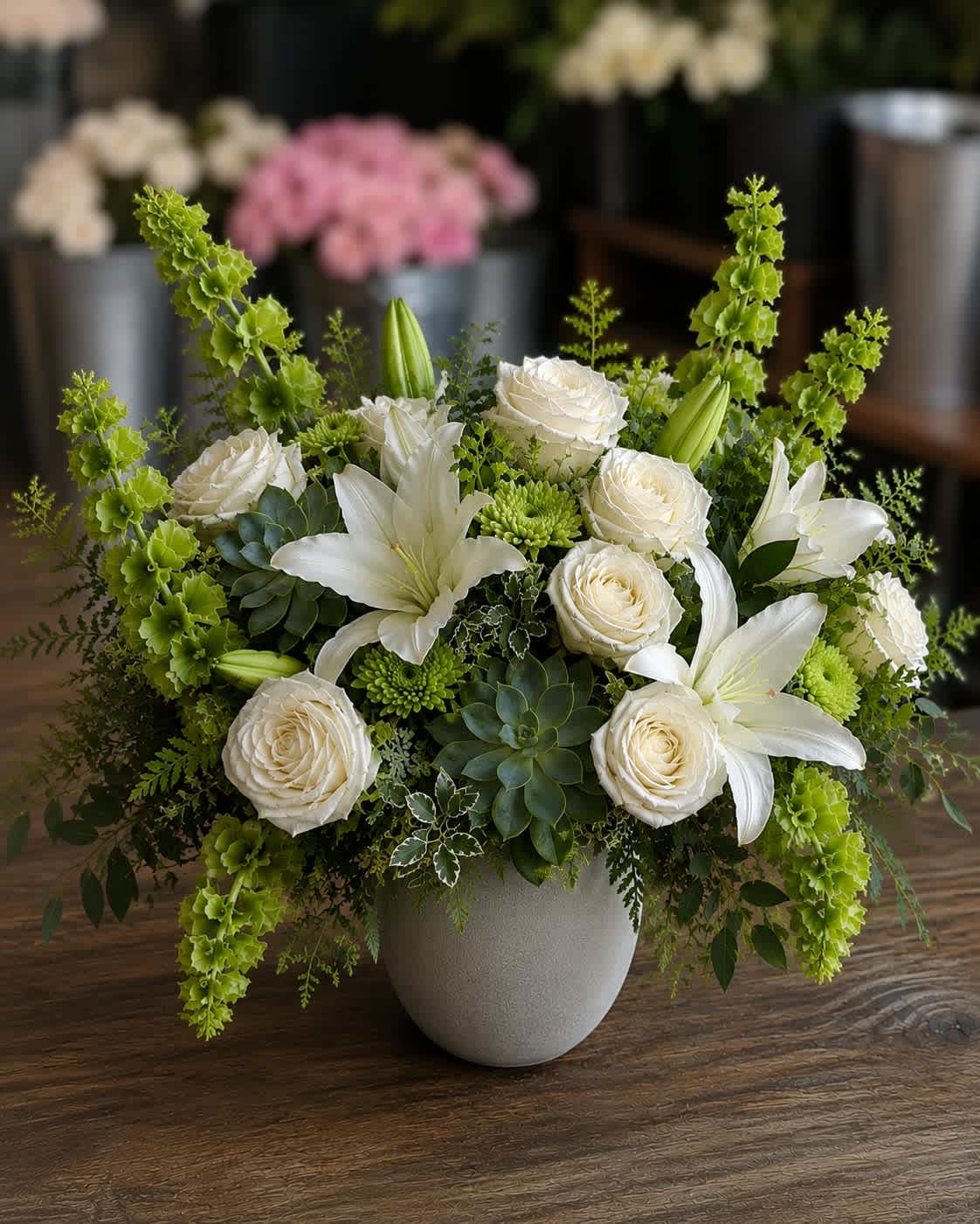 White roses and lilies arranged in a gray vase with green accents