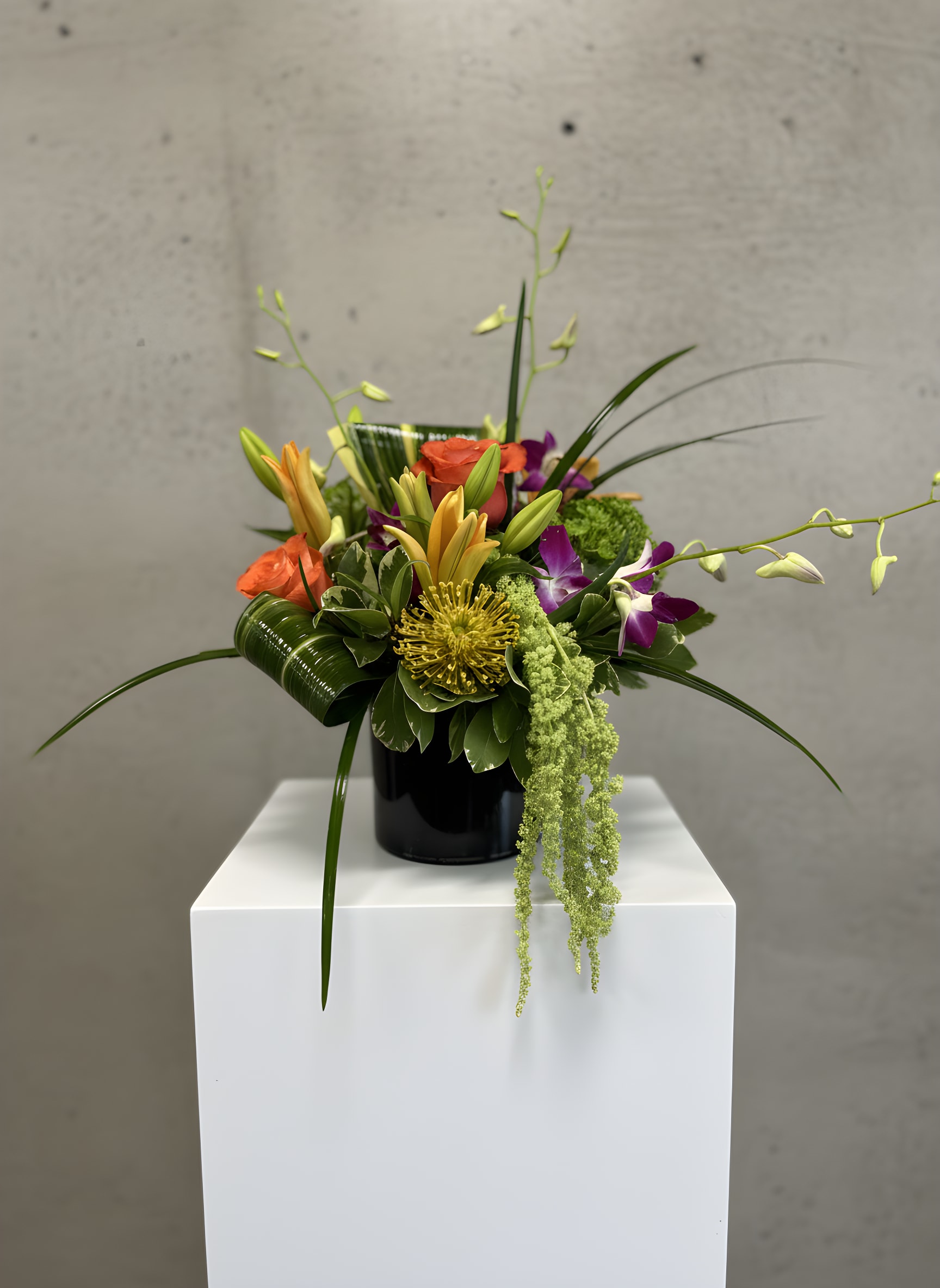 Tropical Noir - Tropical Noir is a bold and modern tropical flower arrangement featuring vibrant orange roses, lilies, exotic purple orchids, lush greenery, and unique tropical accents arranged in a sleek black vase. Perfect for birthdays, congratulations, anniversaries, corporate gifts, thank-you flowers, or any special occasion. Handcrafted by All Occasions Florist, your local Dallas florist, and available for same-day flower delivery in Dallas, TX, and surrounding areas. Send fresh flowers in Dallas with a unique tropical floral arrangement designed to make a lasting impression.
