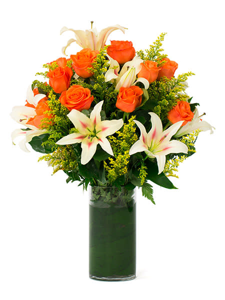 Orange roses and white lilies in a tall glass vase