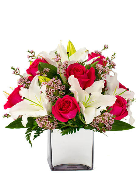 Arrangement of hot pink roses and white lilies in a clear glass cube vase