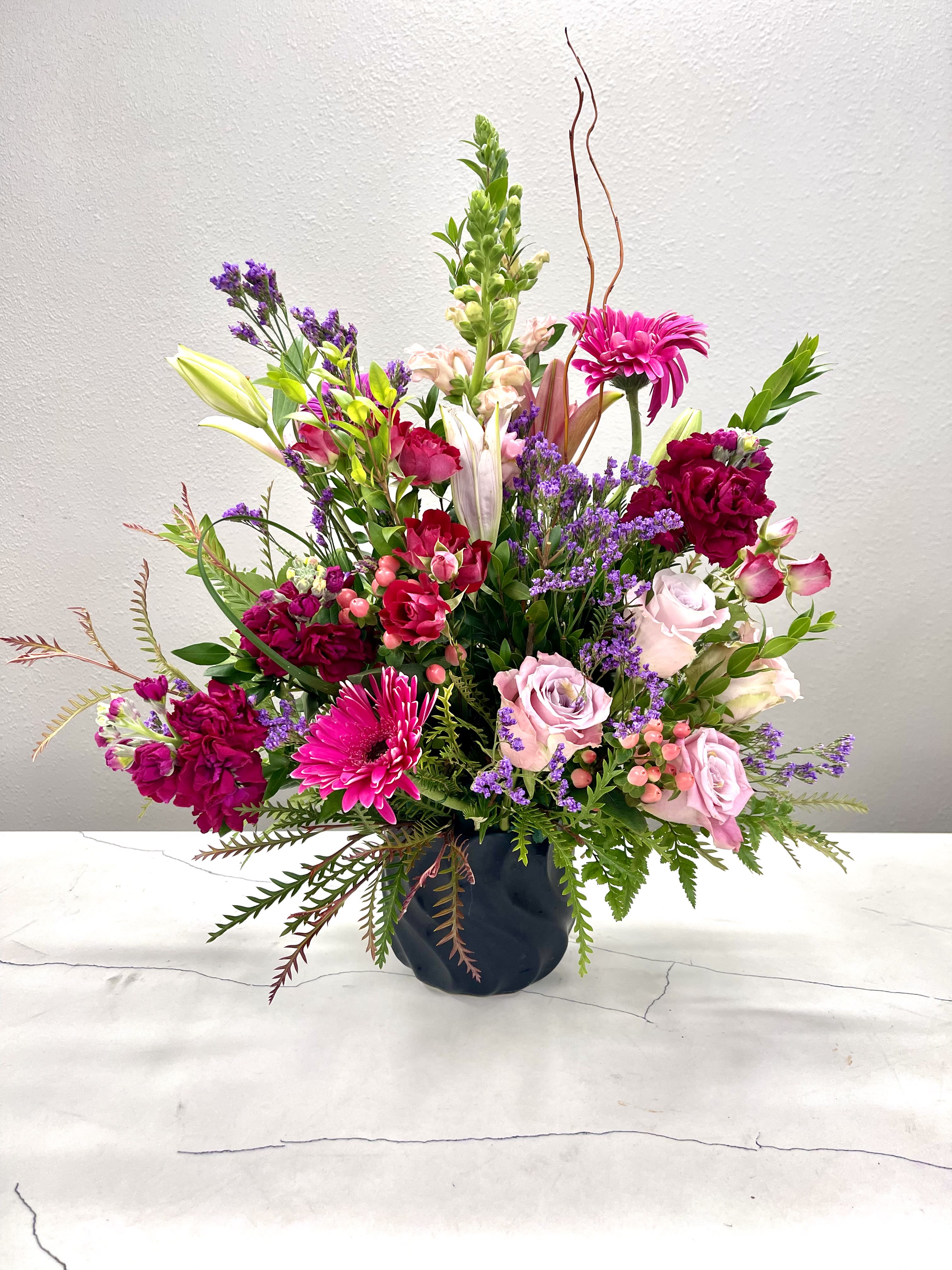 Mixed pink and purple flower arrangement in a dark vase