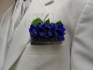 Blue boutonniere pinned to a white suit jacket