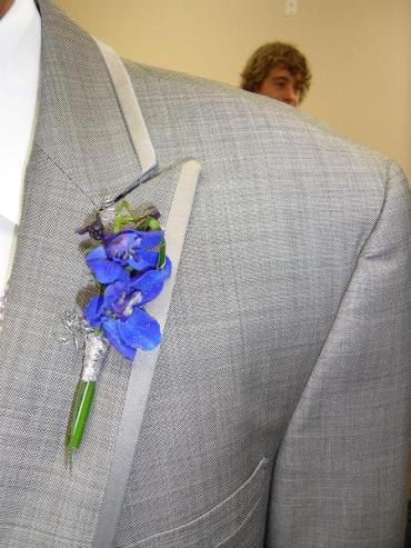 Blue orchid boutonniere pinned to a gray suit jacket