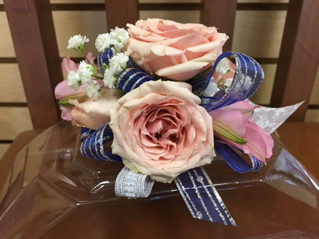 Pink roses with small white flowers and blue ribbon on a clear tray