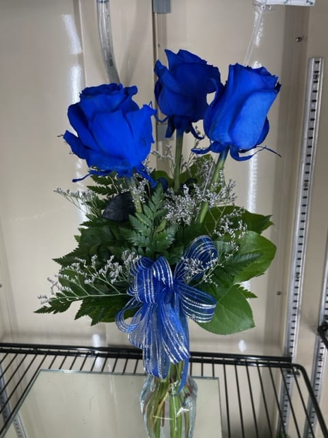 Bouquet of blue roses with a ribbon in a clear vase