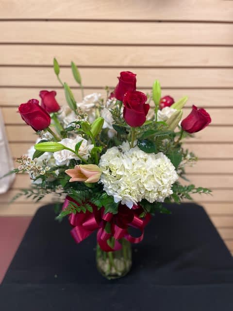 Red roses and white hydrangea in a glass vase with a ribbon