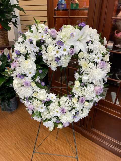 Heart-shaped white floral wreath on a stand with lavender accents