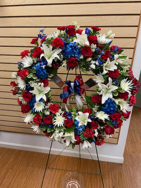Large red, white, and blue floral wreath on a stand with ribbon
