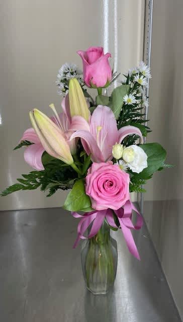 Pink roses and lilies arranged in a clear glass vase