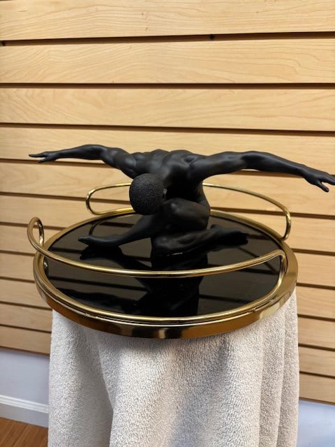 Black sculptural figure on a round mirrored table with gold rails