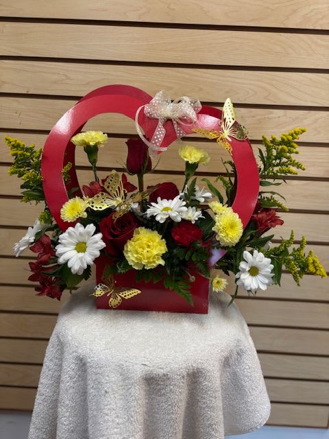 Red basket arrangement with red roses, white daisies, and yellow carnations