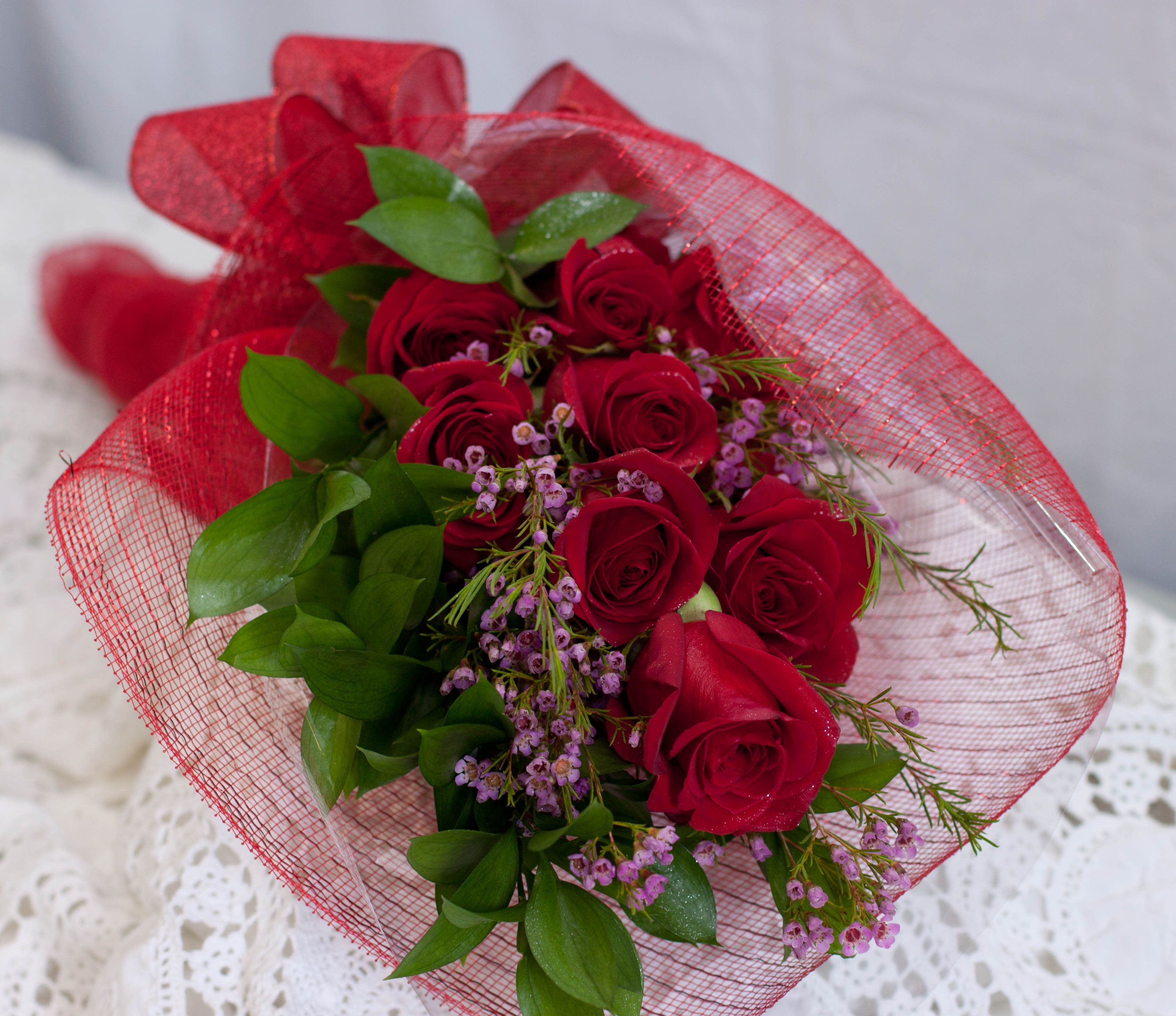 Bouquet of red roses with small purple flowers wrapped in red mesh