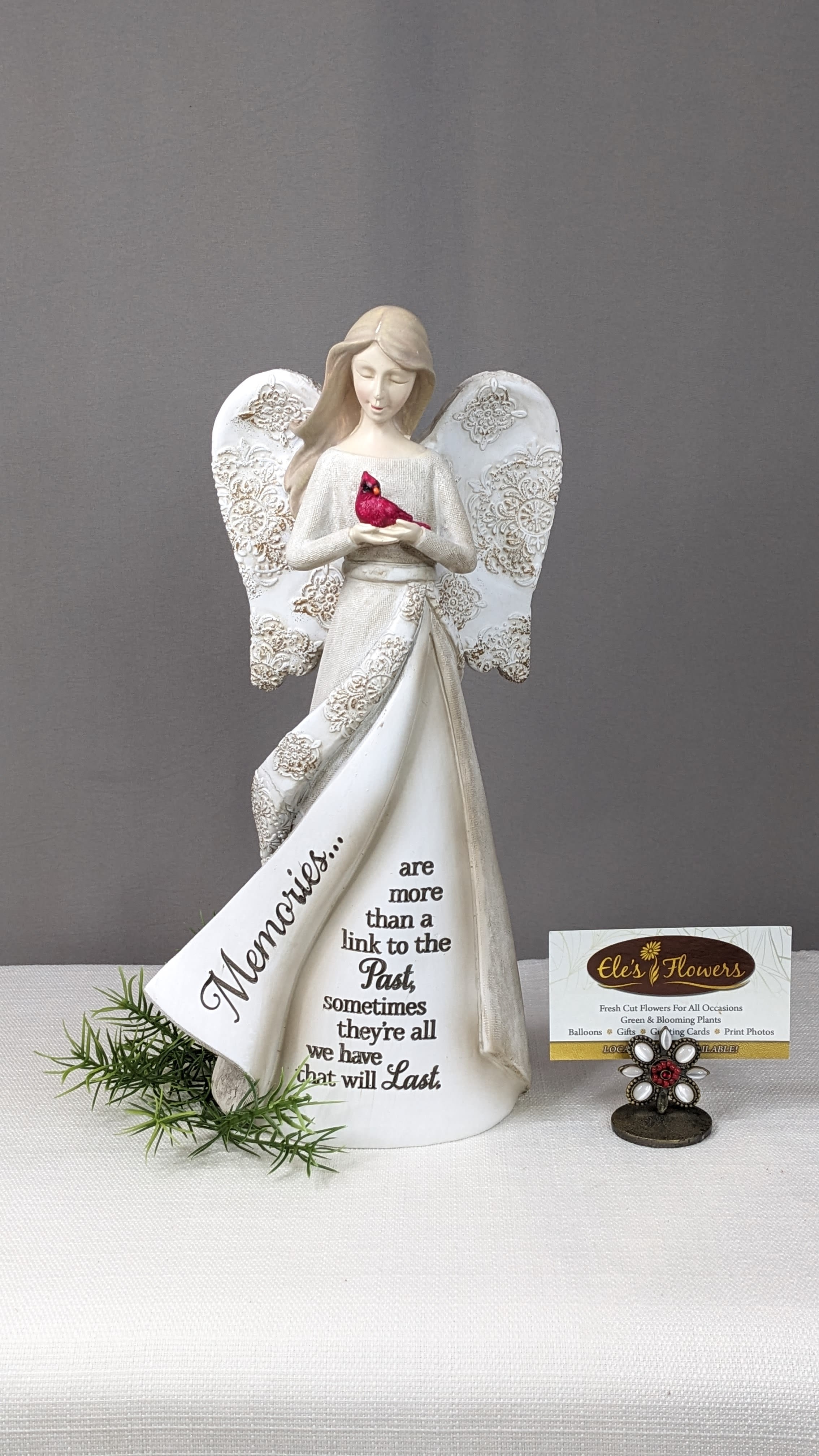 Decorative angel figurine holding a red bird with a memorial message on the dress