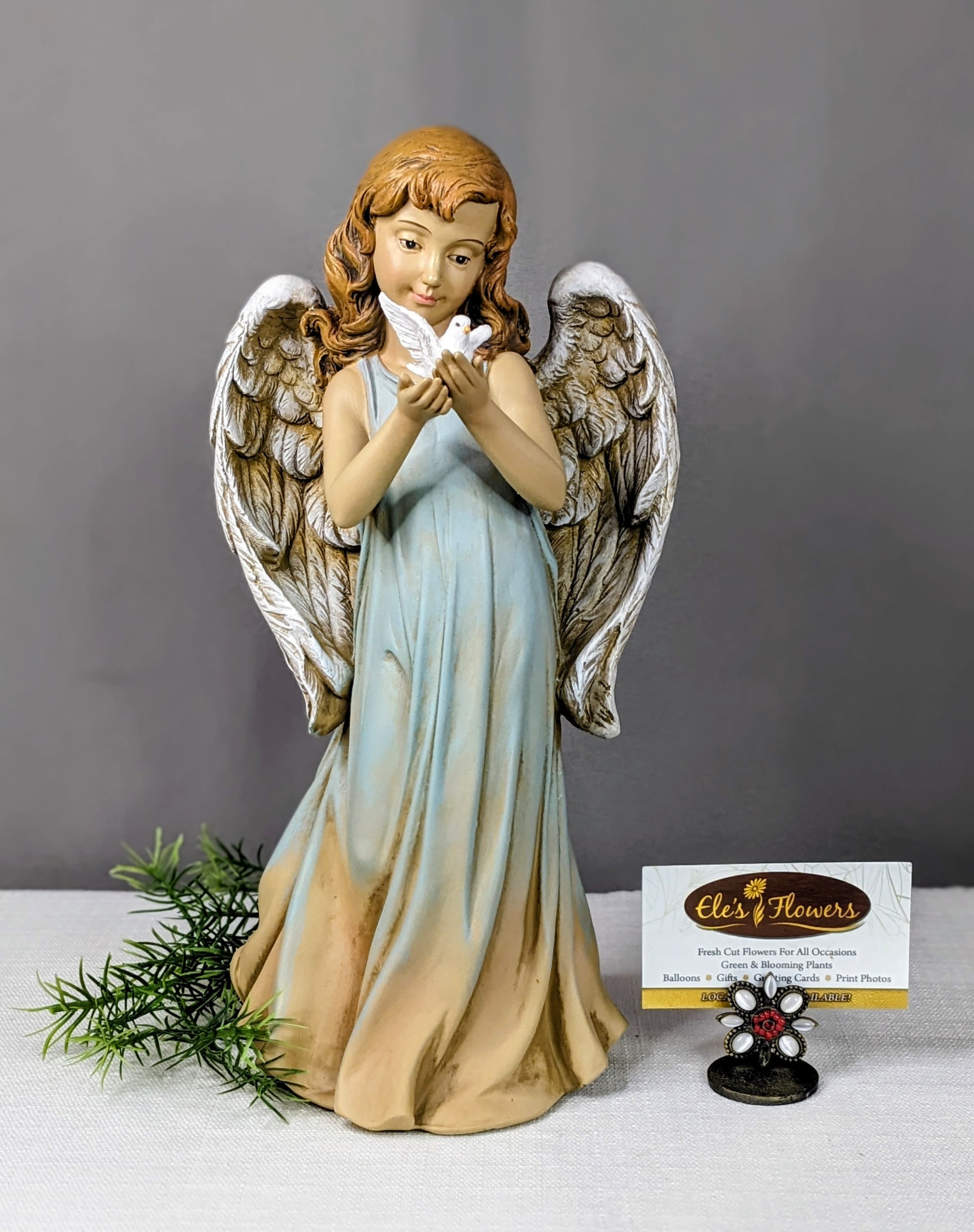 Angel figurine holding a white dove beside a florist card