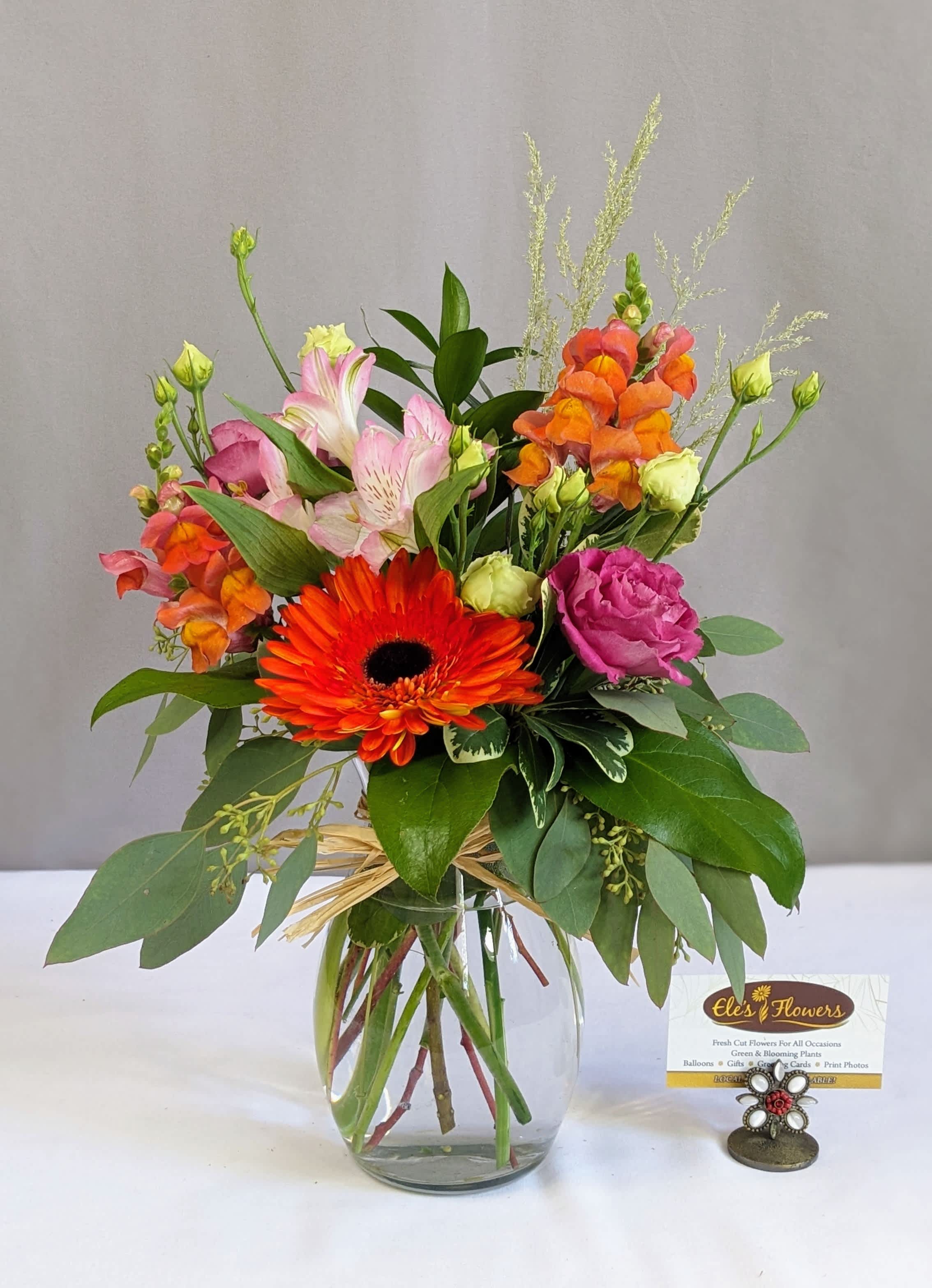 Mixed bouquet in a clear glass vase with orange, pink, and magenta flowers