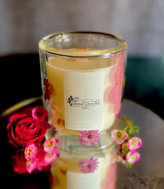 Glass candle with floral decoration beside a red rose