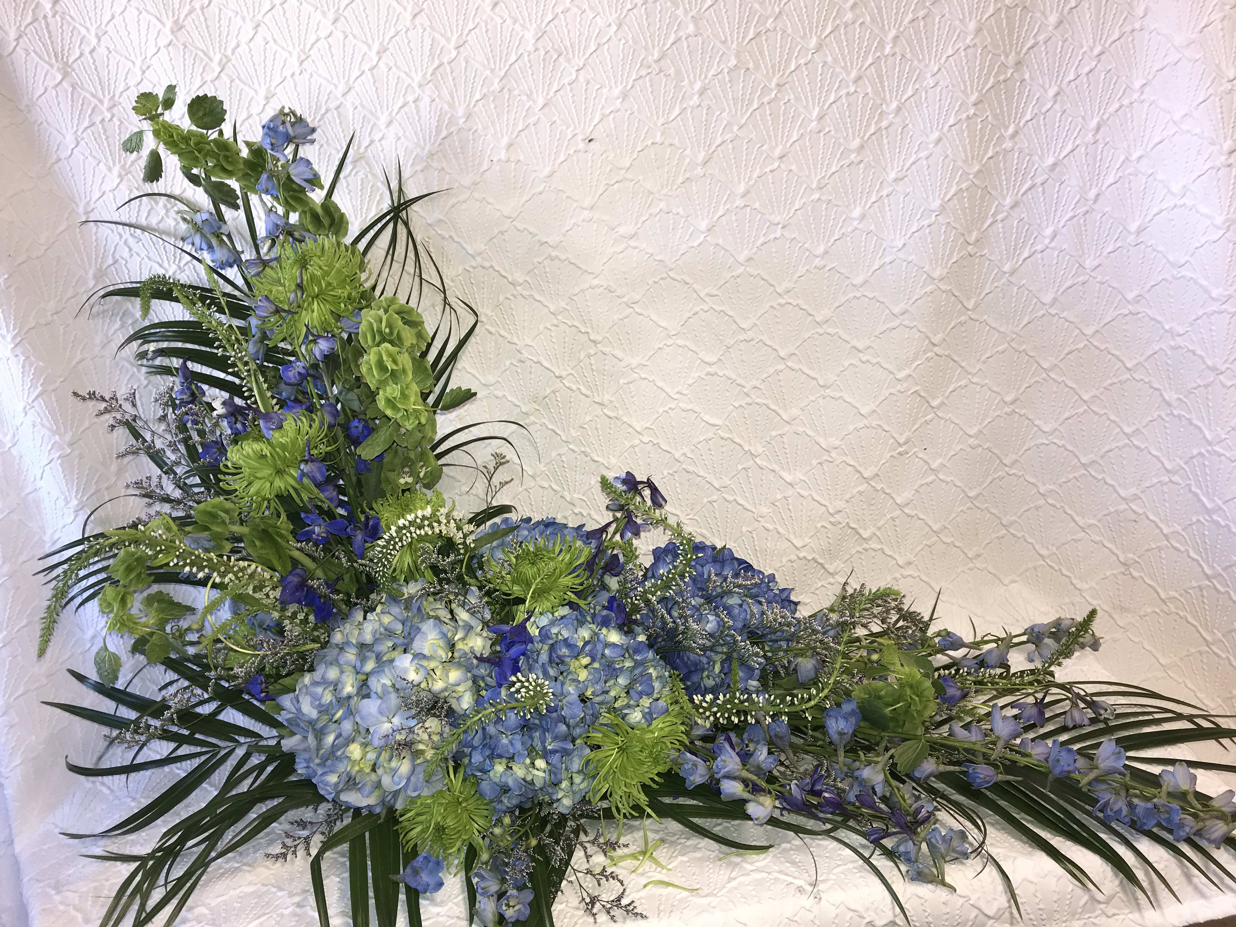 Blue and green floral arrangement with hydrangeas and tall spiky blooms