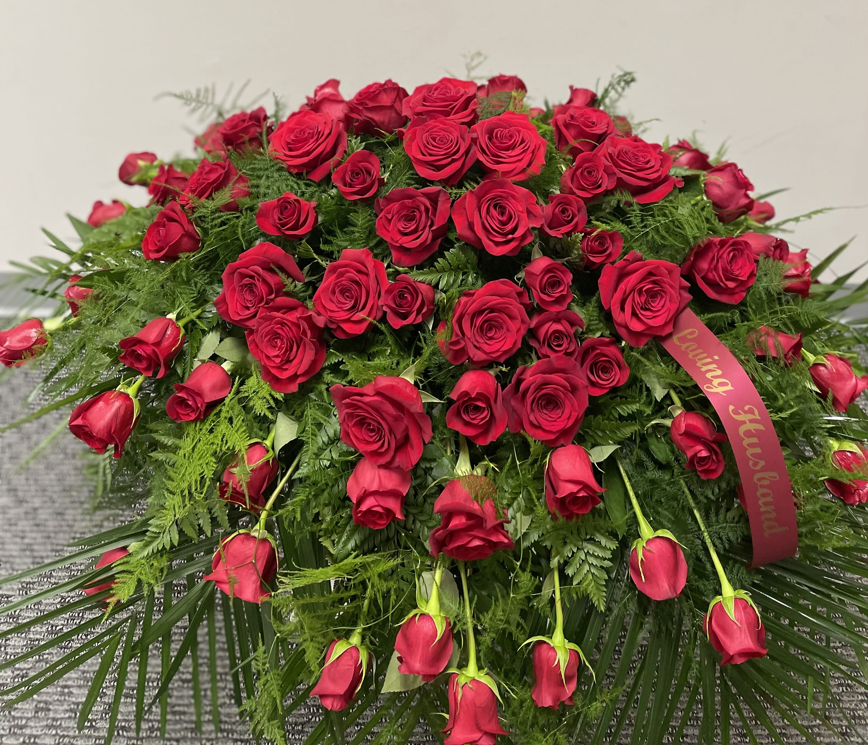 Large red rose arrangement with a ribbon and trailing roses