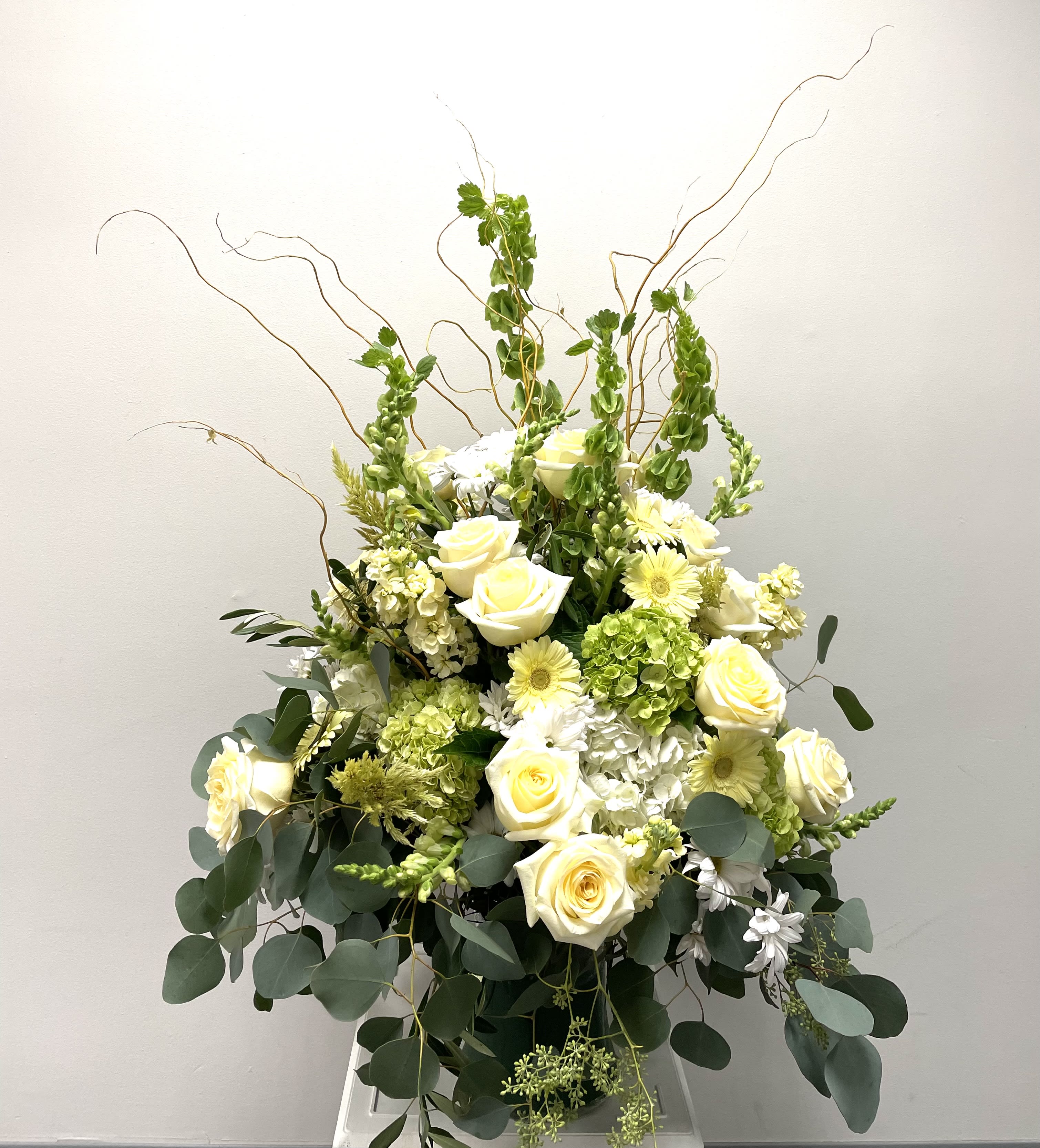 Tall white and pale yellow floral arrangement with roses and daisies