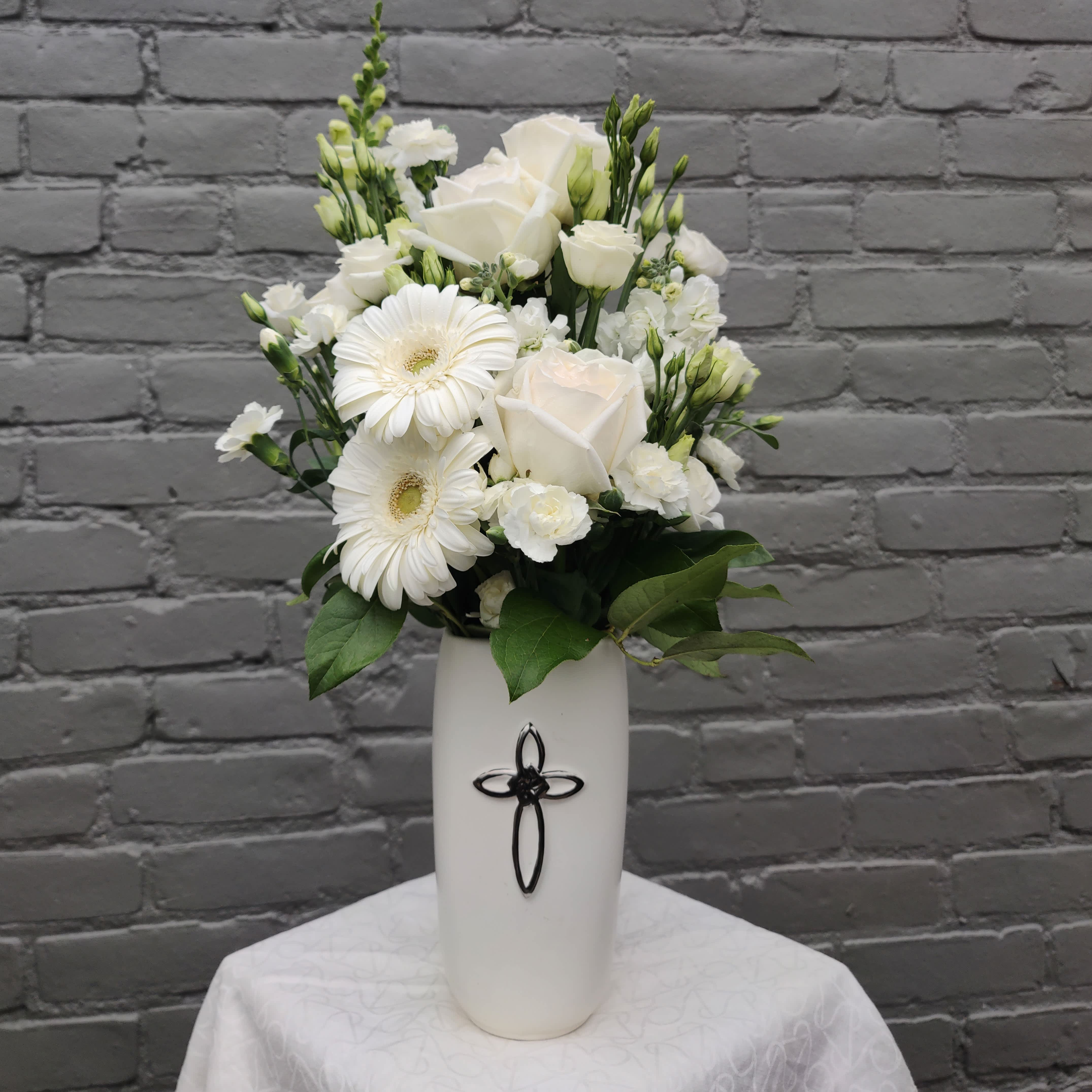 White roses and gerbera daisies in a tall white vase