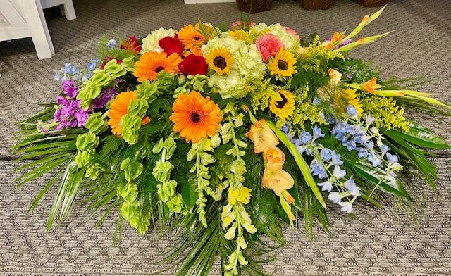 Large colorful floral spray with gerbera daisies, roses, and orchids