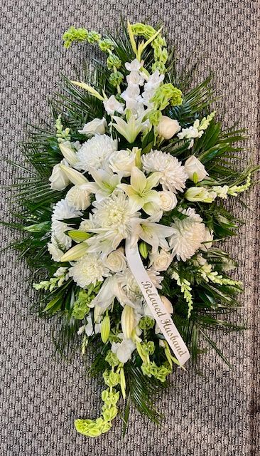 True Sympathy - An all white tribute, this funeral spray is pure and tranquil. Featuring a variety of white flowers and green palms this elegant funeral spray brings a feeling of peace to it's surroundings 