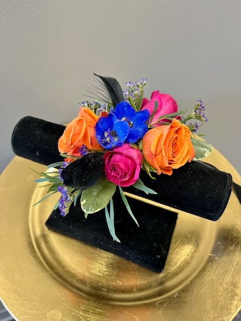Small bouquet of orange, pink, and blue flowers on a black stand