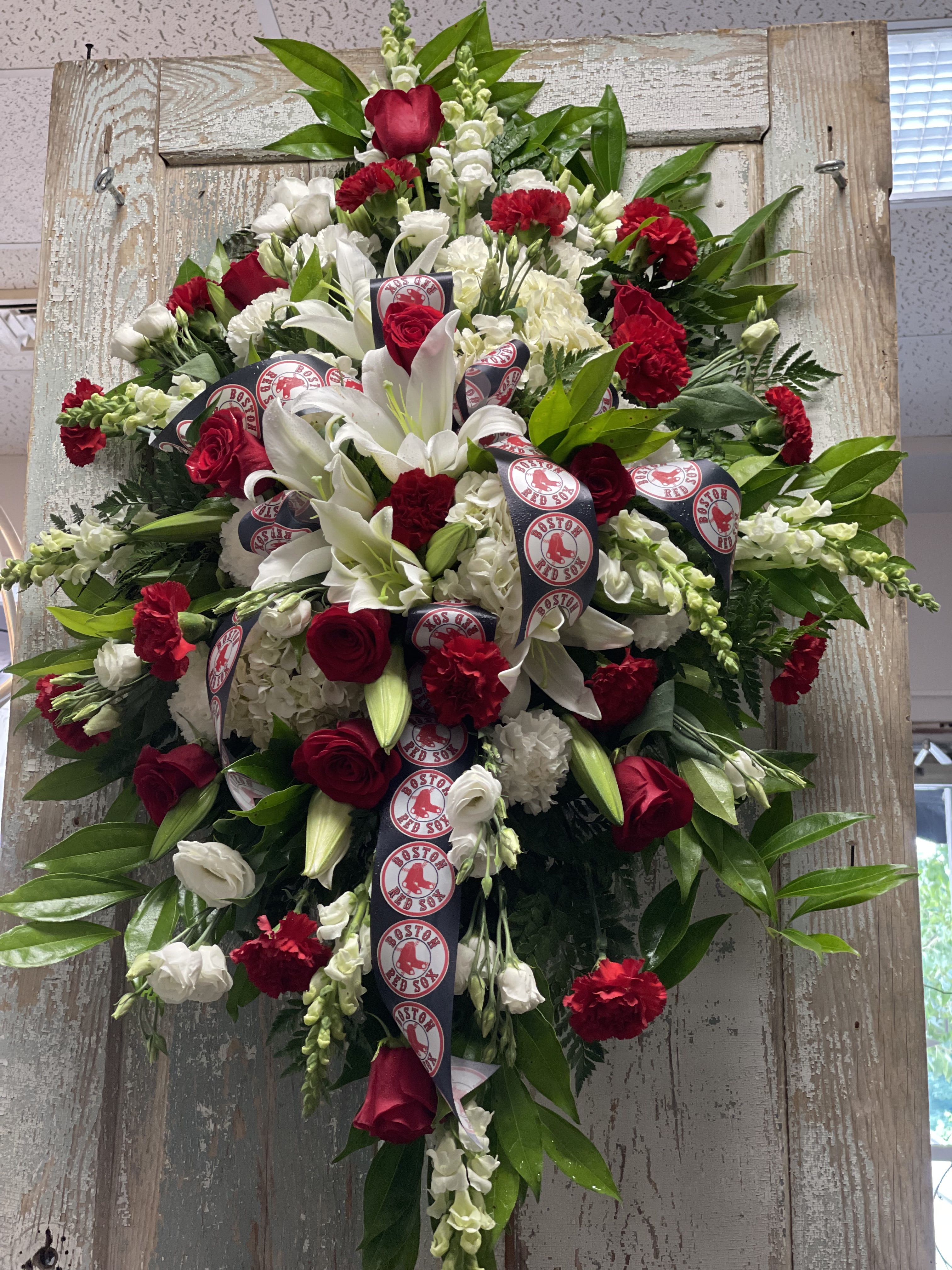 MLB Fan Tribute Standing Spray - This Standing Spray pays tribute to a devoted baseball enthusiast with fresh seasonal flowers arranged around a baseball themed keepsake.