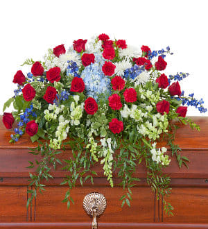 Red roses with white and blue flowers arranged on a wooden casket