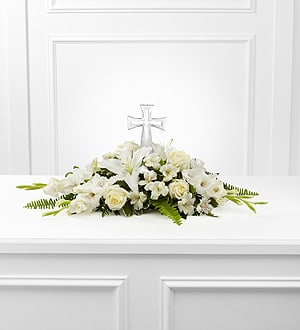 White floral casket spray with a clear cross centerpiece
