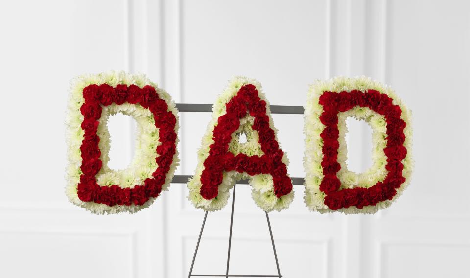  Remembering Dad - Remembering Dad Arrangement is the perfect way to  commemorate your father at his final farewell service.  White  chrysanthemums and red mini carnations are beautifully arranged to form the word, ""Dad,"" to create a wonderful way to express the love you have  for the man that gave you so much throughout the years. Can also be arranged to spell the name "Mom". 