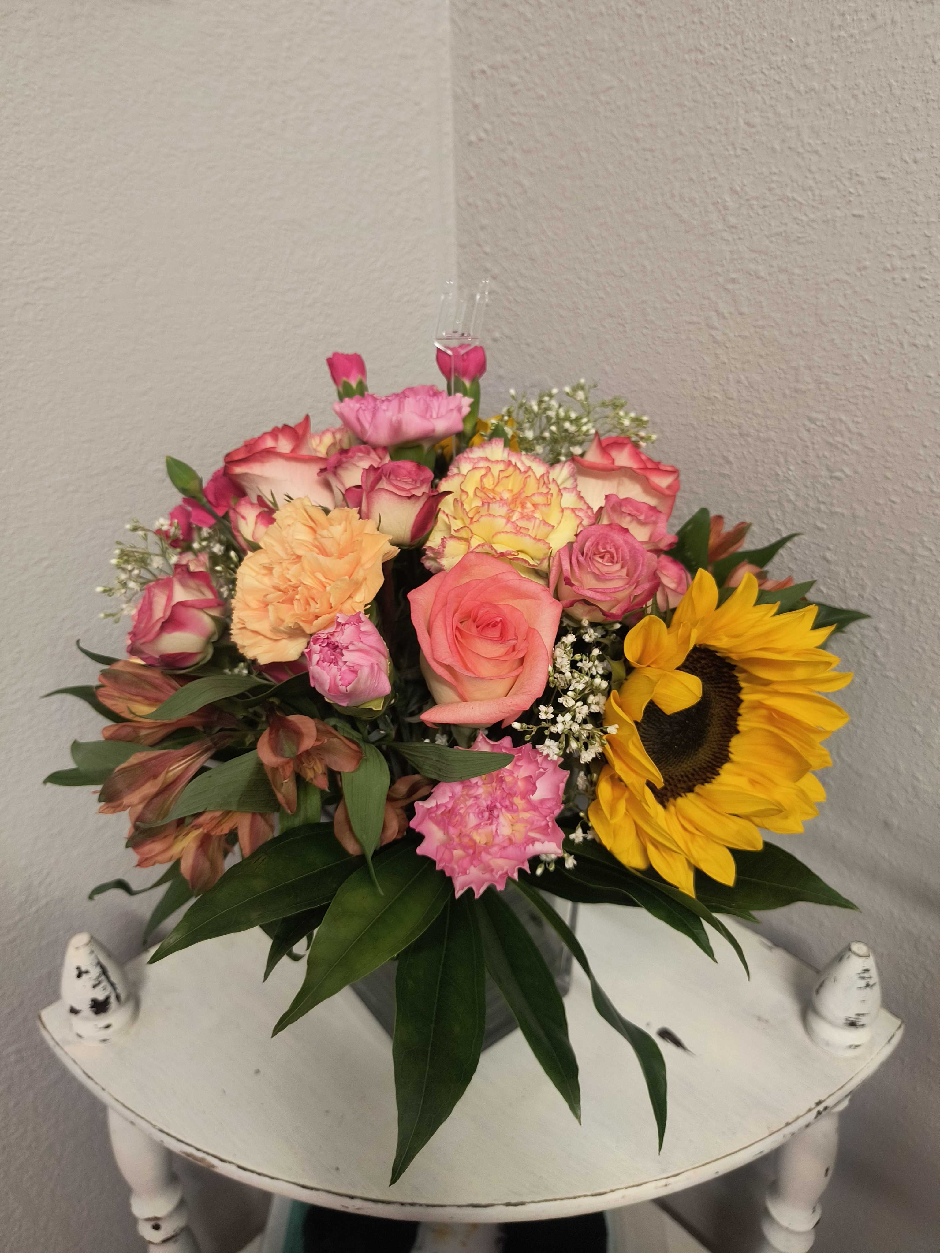 Mixed bouquet of roses, carnations, and a sunflower in a vase