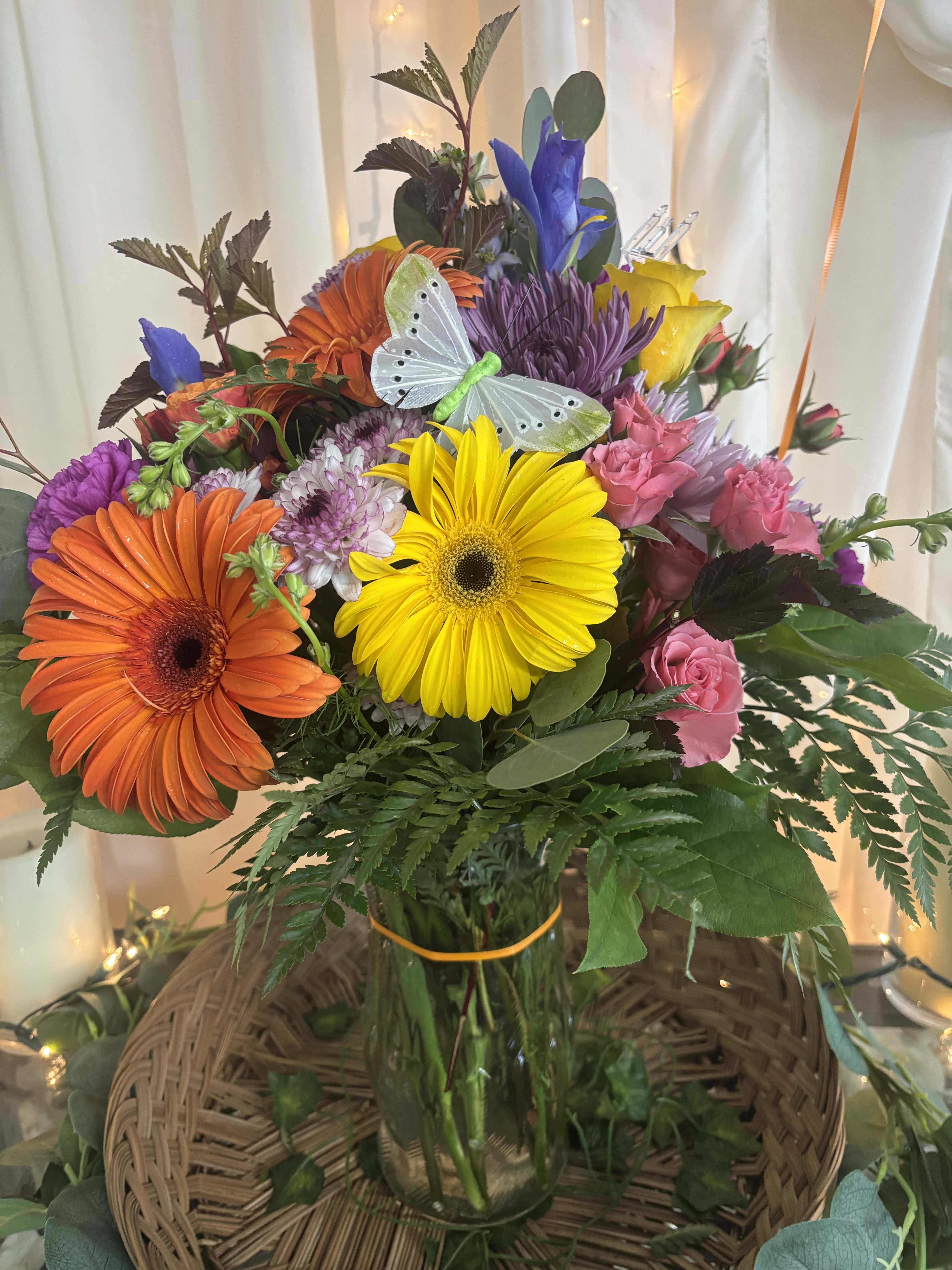 Colorful mixed bouquet in a glass vase with a butterfly decoration