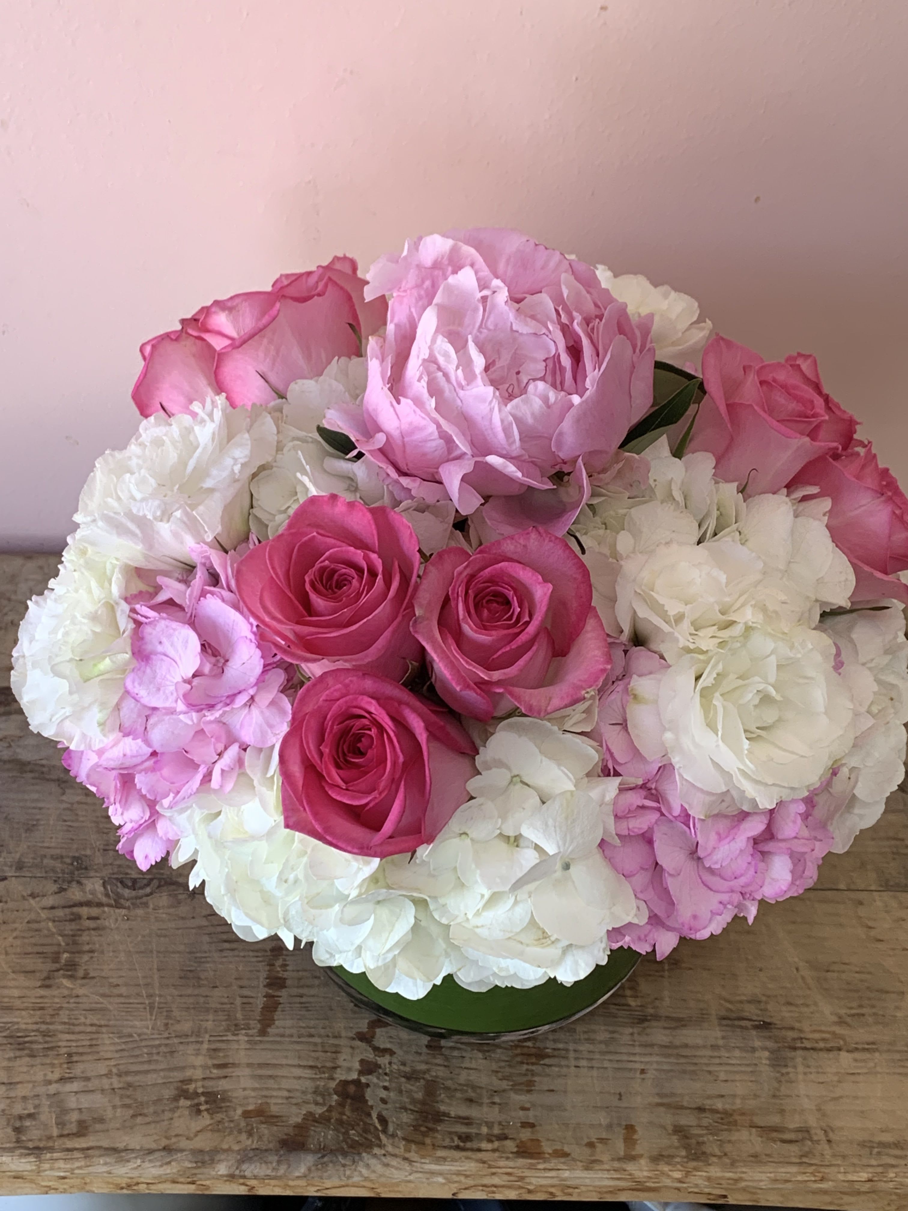 Pink roses and white hydrangeas arranged in a low round container