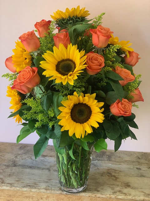 Sunflower and peach rose bouquet in a clear glass vase