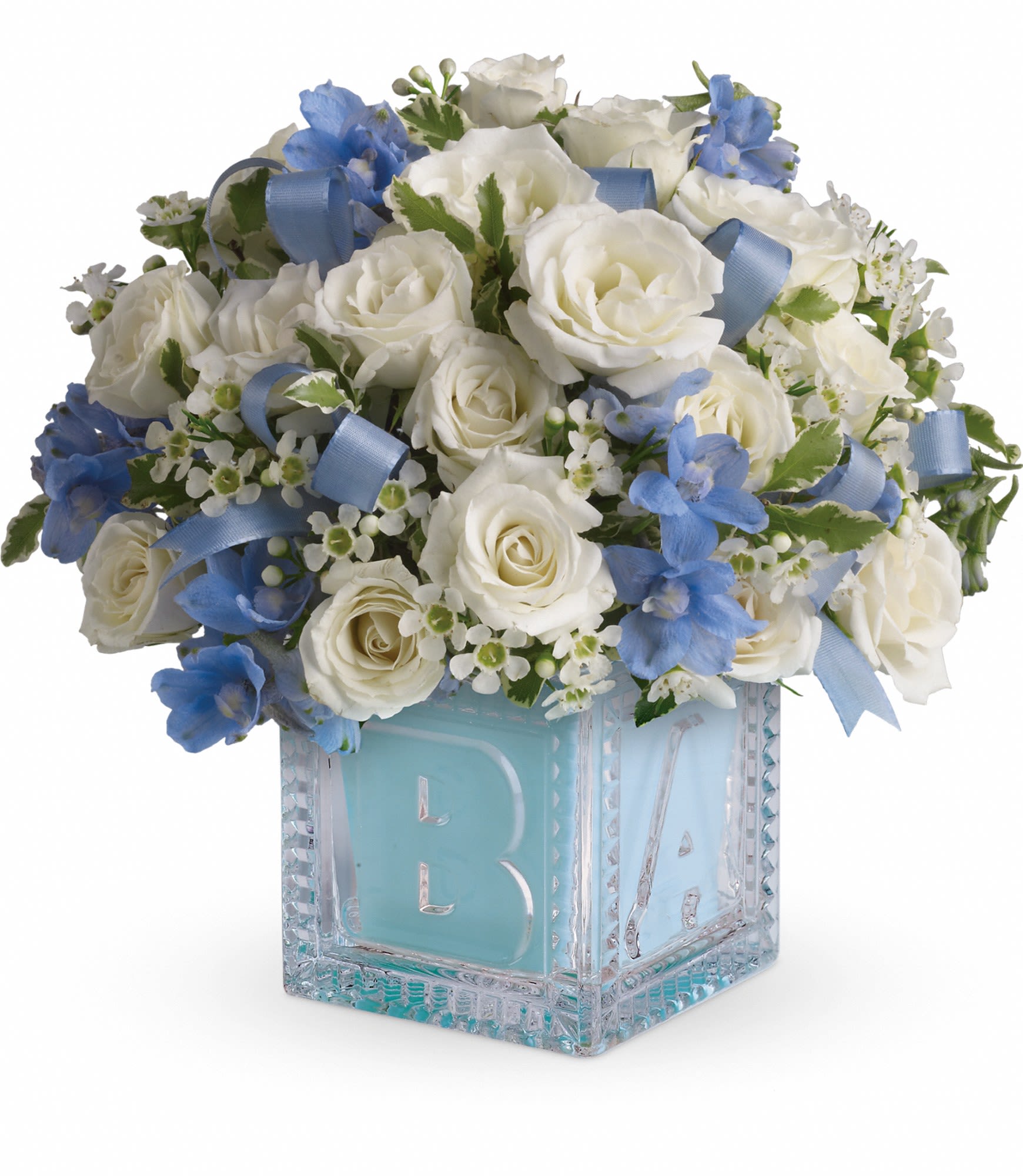 White roses and blue flowers in a glass block vase with a blue ribbon