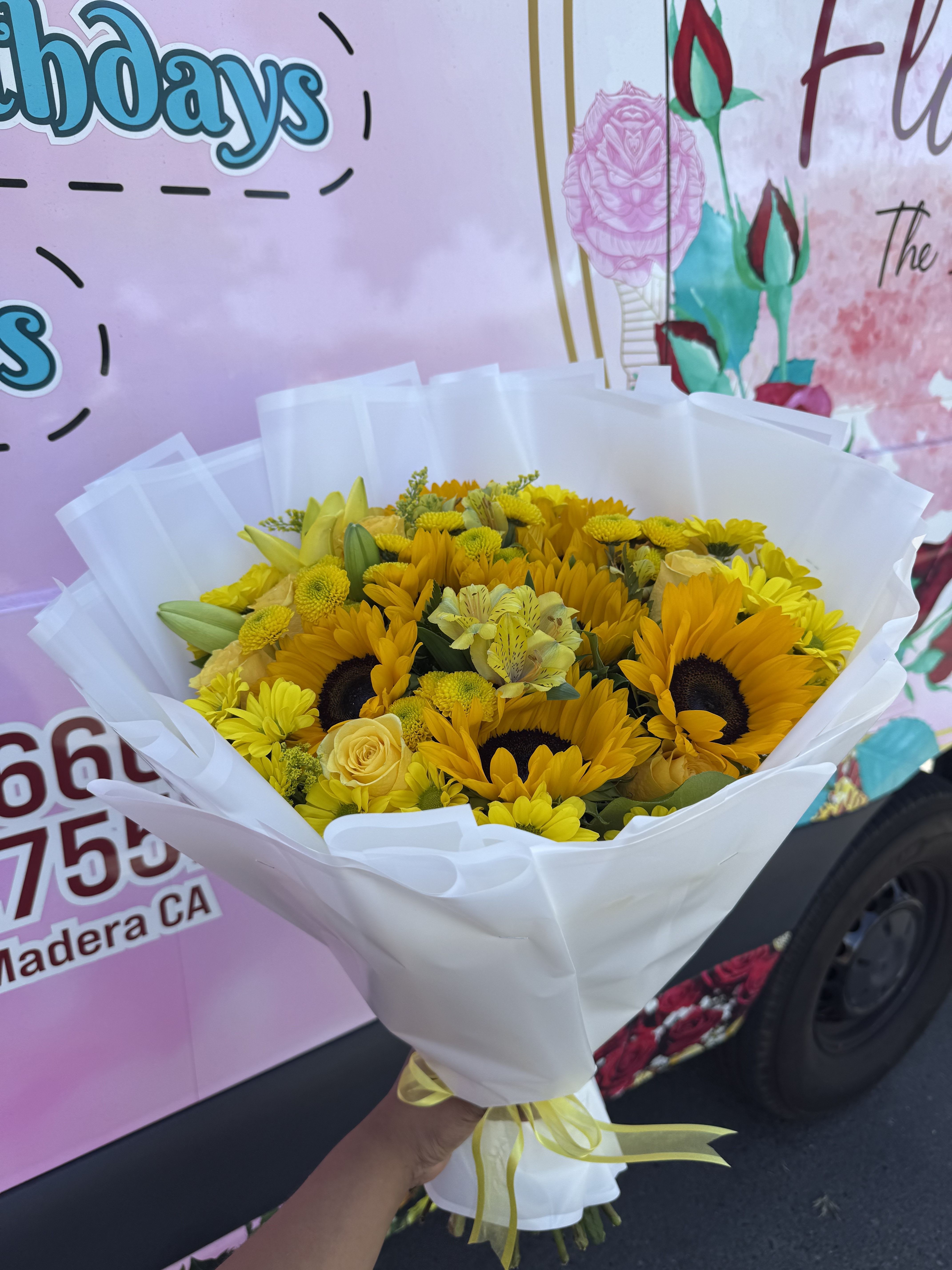 Bouquet of yellow sunflowers and roses wrapped in white paper