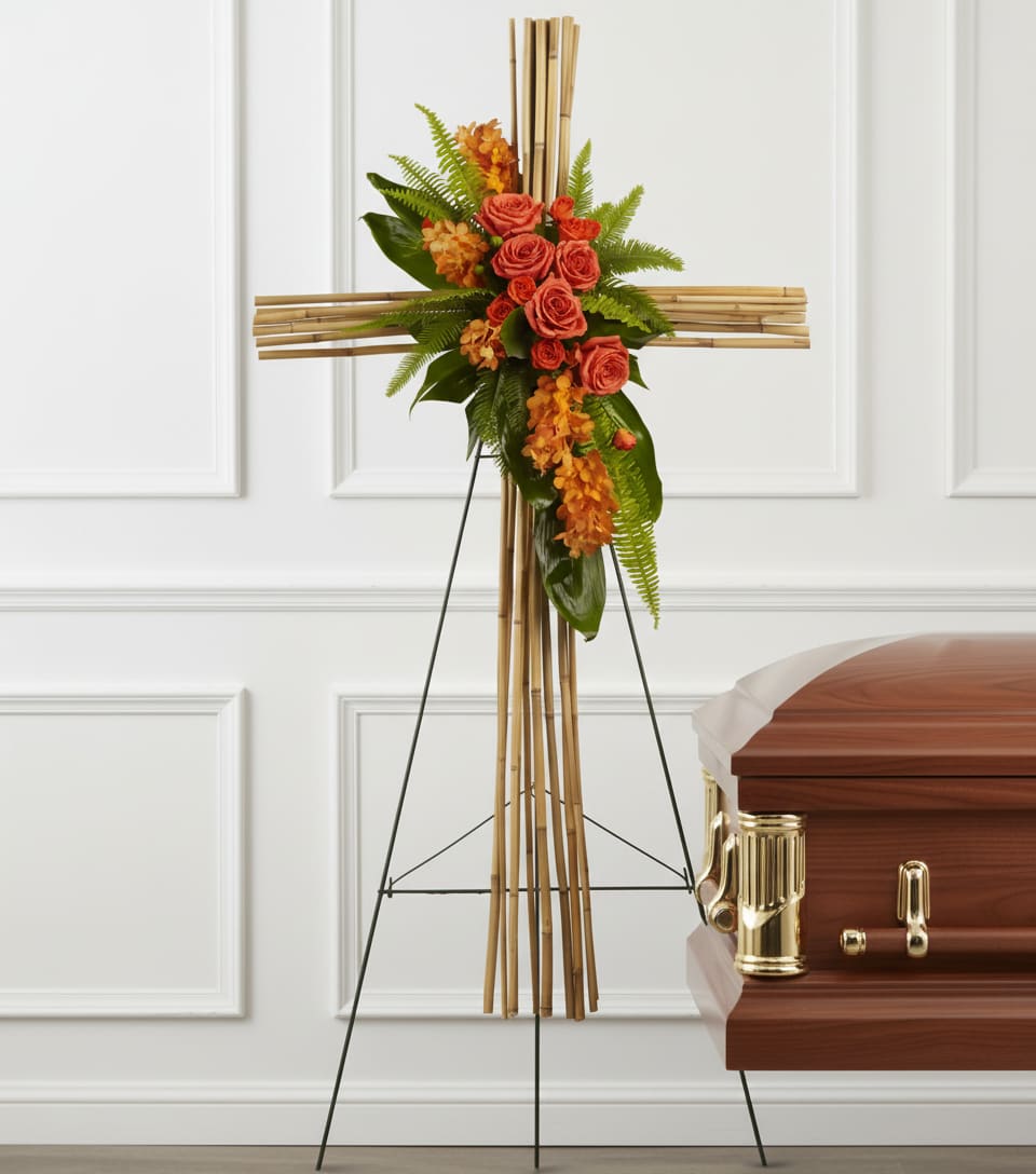Floral cross on an easel beside a casket