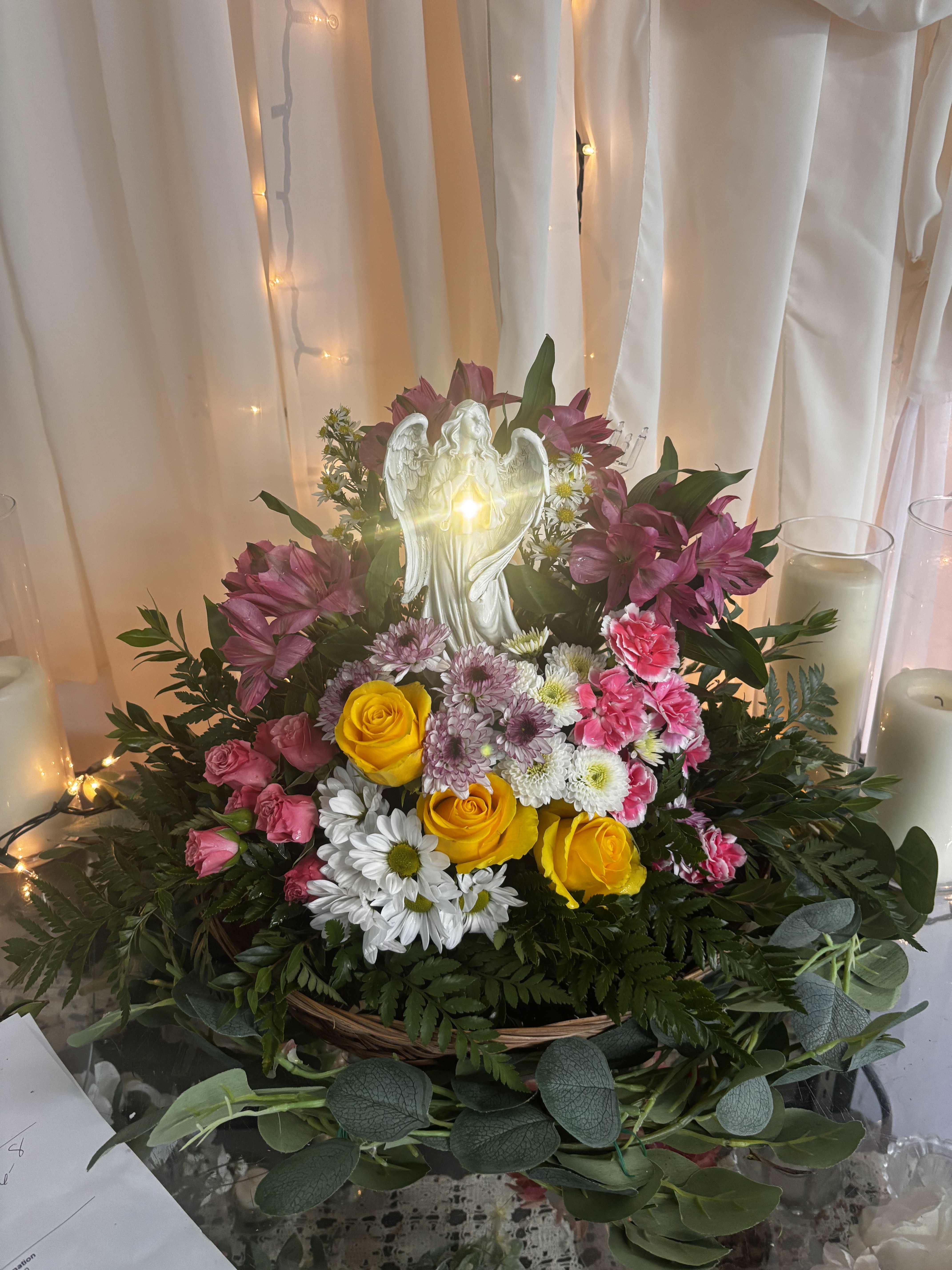 Mixed flower arrangement with roses, daisies, and an angel figurine