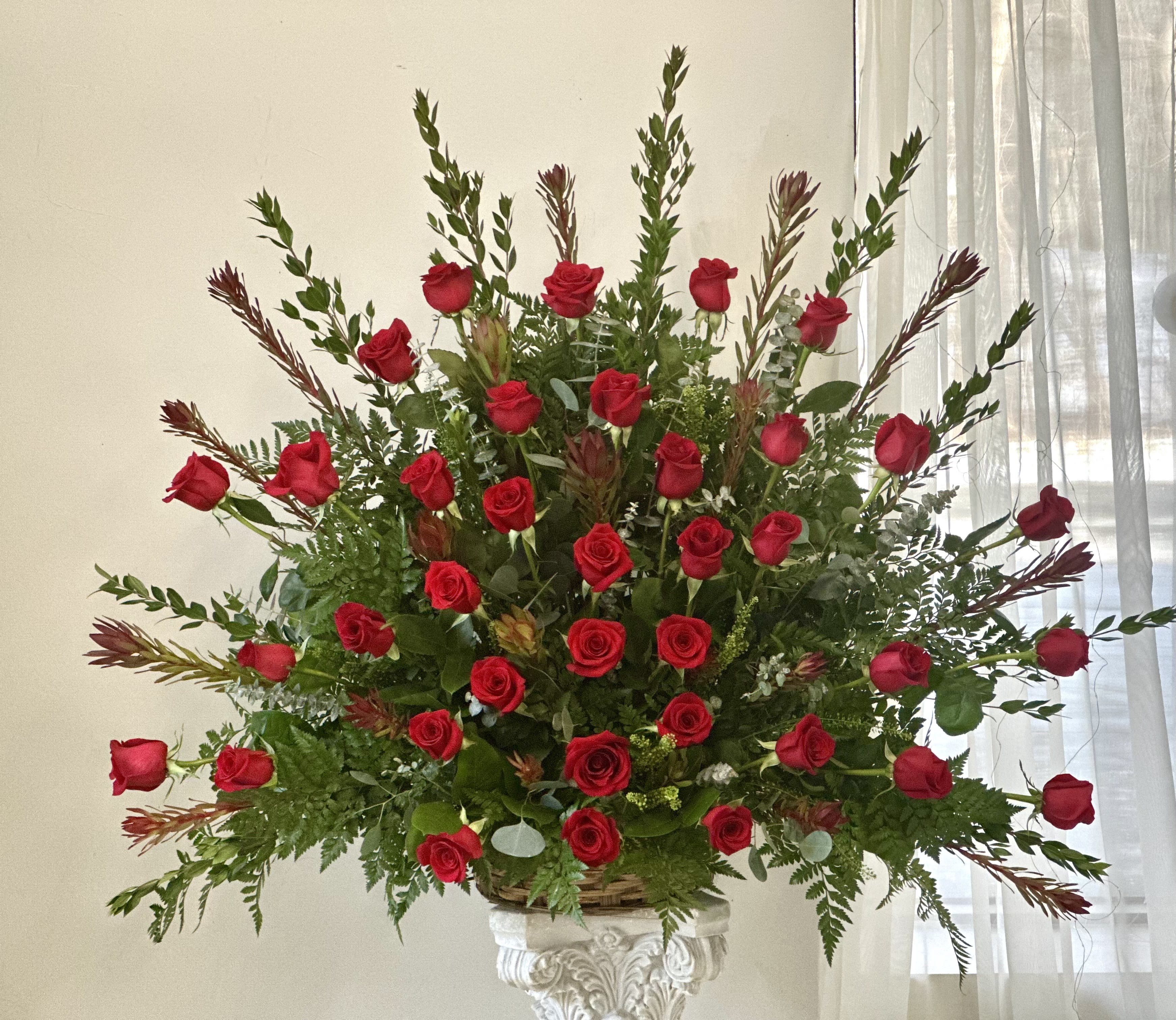 Large arrangement of red roses in a decorative pedestal vase