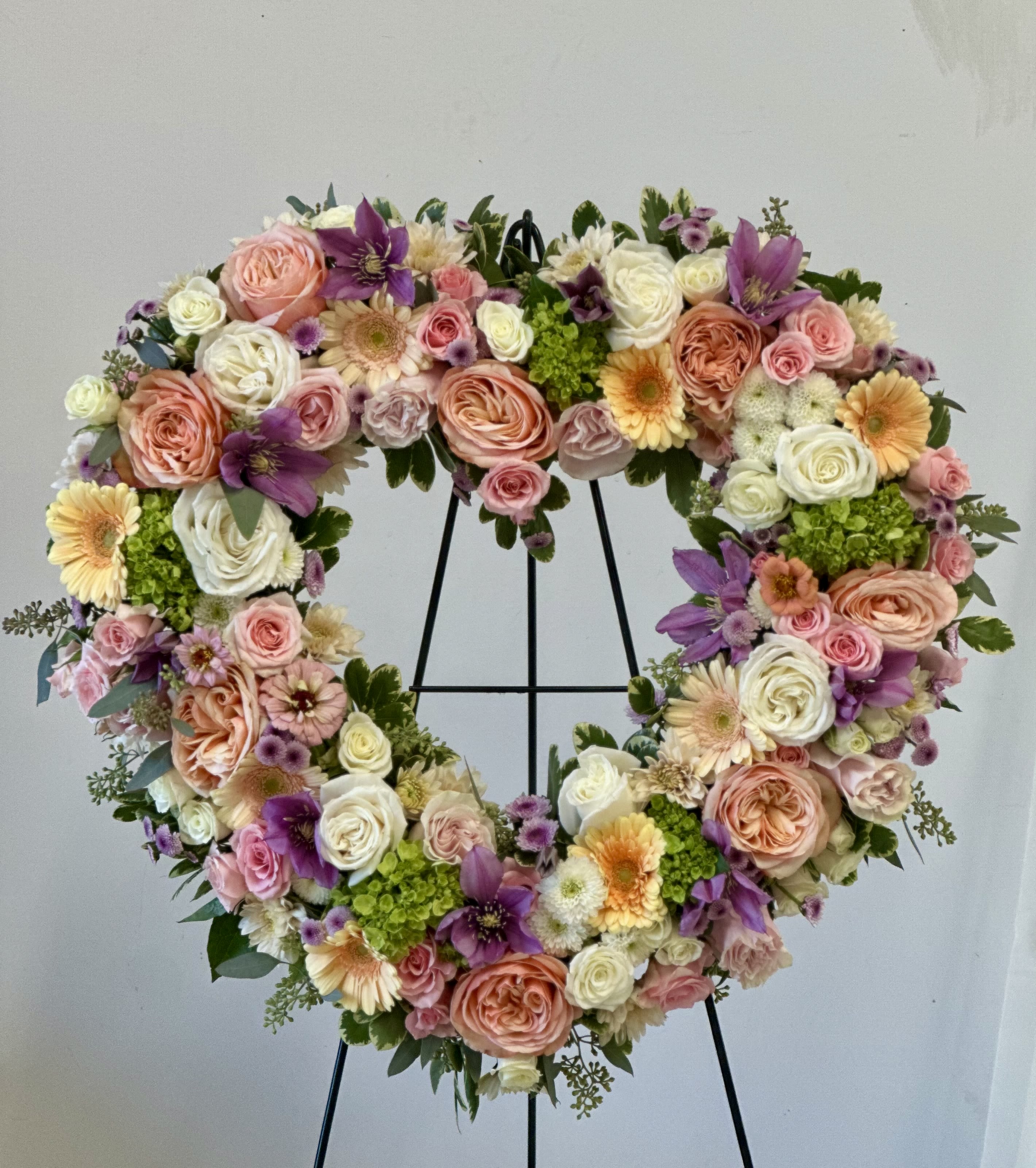 Heart-shaped floral wreath with pink, white, purple, and peach blooms
