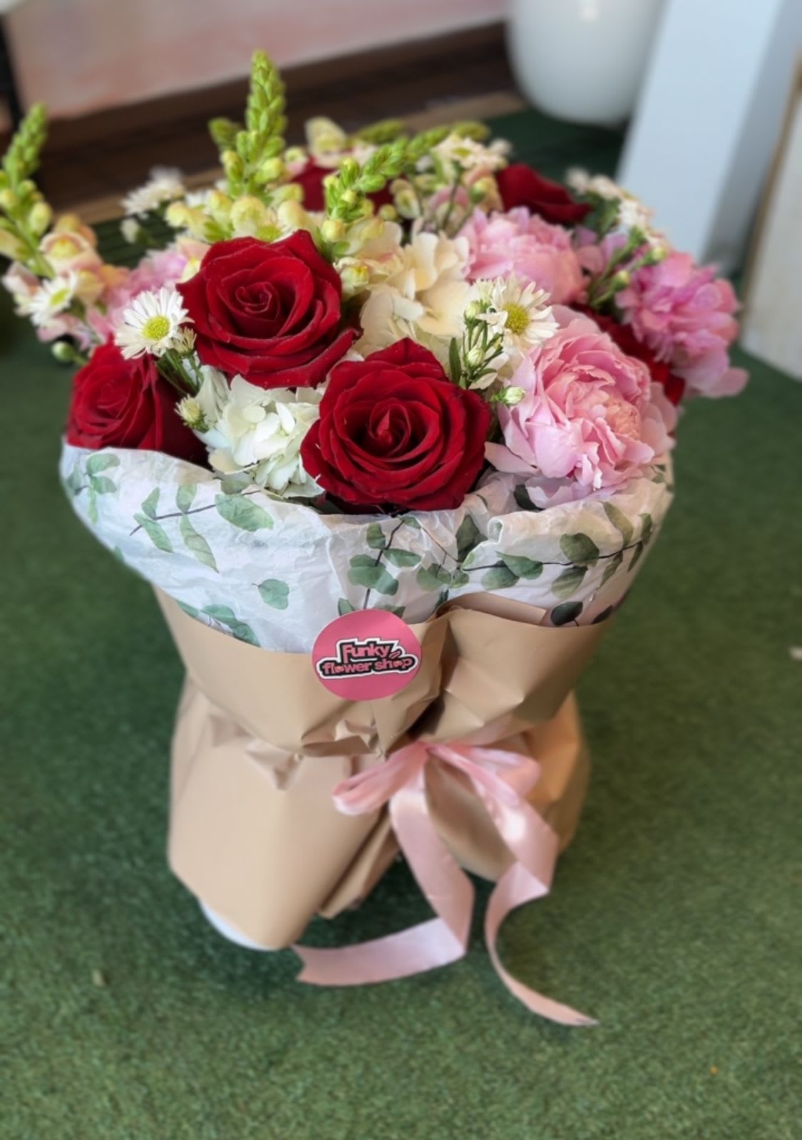 Bouquet of red and pink roses with white blooms in brown paper wrap