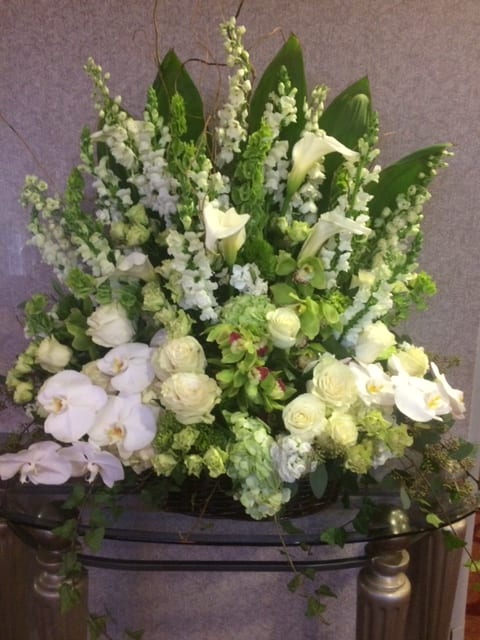 Large white and green floral arrangement with orchids and calla lilies